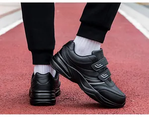 Close-up of black men's walking shoes with Velcro straps on a red outdoor track