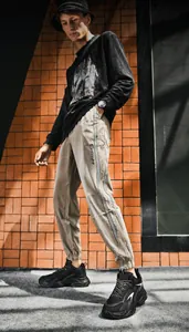 Detail of khaki jogger pants with side stripe and logo on street style model