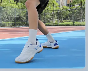 Vue détaillée de chaussures de badminton blanc et bleu avec semelle en gomme sur terrain
