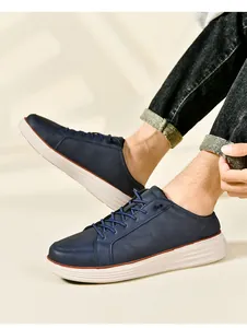 Detail of navy blue leather slip-on loafers with thick white sole and brown trim