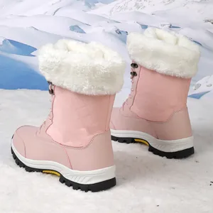 Detalle de botas de nieve rosas con cuello de piel sintética blanca y satén acolchado