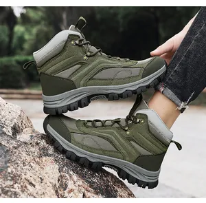 Close-up of olive green hiking boots with deep tread rubber soles on rocky outdoor terrain