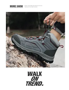 Detail of man lacing up grey outdoor hiking boots with red accents and thick rubber soles