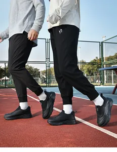 Outdoor action shot of black winter thermal walking shoes and matching joggers on a red track