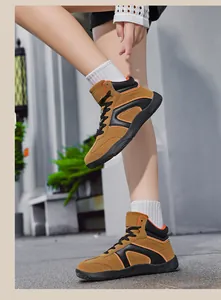 Detail of high-top hiking sneakers in tan nubuck with orange stitching and thick rubber soles
