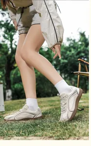 Primer plano de zapatillas de cuero crema con suelas marrones antideslizantes sobre césped