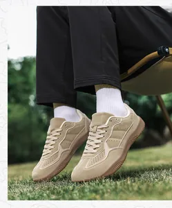 Close-up of beige suede casual sneakers with breathable holes on grass background