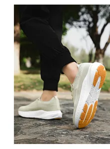 Détail d'une chaussure de marche légère en tricot avec semelle EVA blanche et renfort orange