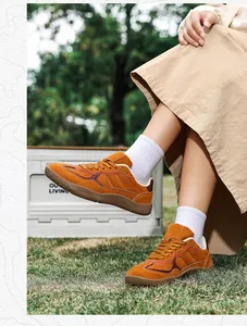 Outdoor close-up of tan nubuck leather sneaker with vintage red and brown wave stitching