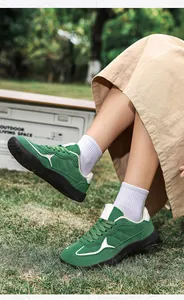 Close-up of dark green suede sneaker with white wavy stripes on outdoor grass