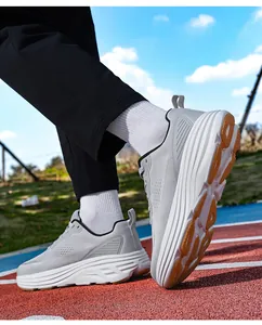 Vista esterna di scarpe da corsa grigio chiaro a pianta larga su pista di atletica
