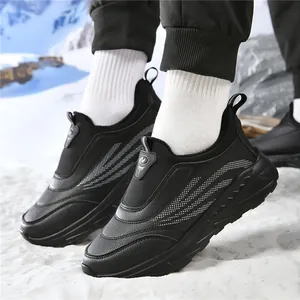 Waterproof winter walking shoes in black leather with non-slip soles on snow