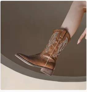 Detail of dark brown cowboy boots with intricate embroidery and a classic pointed toe