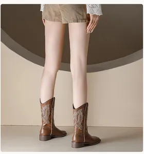 Detail view of brown western cowboy boots with intricate white embroidery and chunky heel