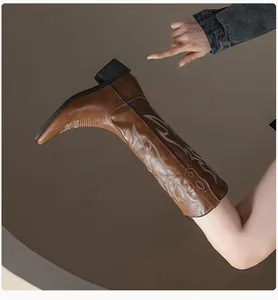 Detail of vintage brown cowboy boots with white embroidery and chunky heels for women