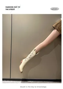 Close-up of beige cowboy boots featuring intricate hollow out embroidery and block heels