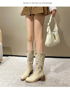 Detail of cream western boots with embroidery and chunky heels worn by a model