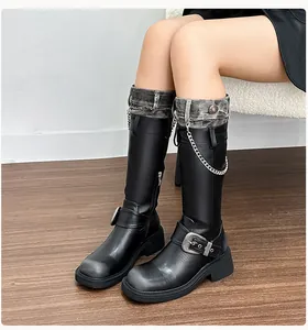 Detail of knee-high boots with denim-style cuffs, metal chains, and thick platform soles