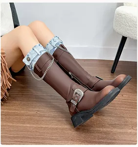 Close-up of brown tall boots featuring metallic chains and vintage carved buckles