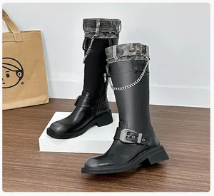 Detail of black boots with denim patchwork, metal chains, and platform soles