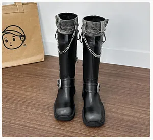 Detailed macro of black knee-high boots with denim patchwork and silver metal chains