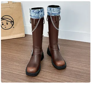 Close-up of vintage brown leather boots featuring denim lining and metal chain details