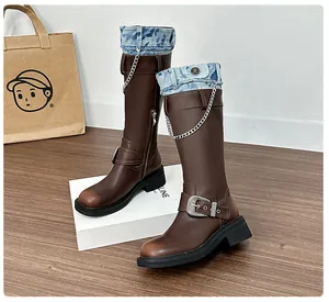 Detail of dark brown chunky boots with denim patchwork, silver chains and side zippers