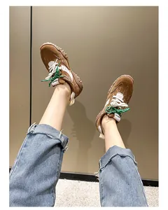 Primer plano de zapatillas de plataforma en ante marrón con cordones dobles verde y blanco