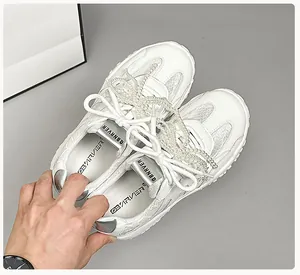 Details von weißen Leder-Sneakern im Ballett-Stil mit Perlenkette und Spiegelbesatz
