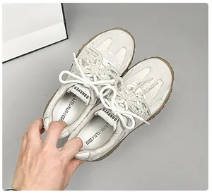 Draufsicht auf beige Leder-Sneaker mit eleganten Perlenketten und Gummisohlen-Detail