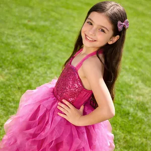 Detail of sequined rose red girls party dress with matching bow headband on green grass