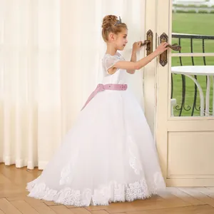 Dettaglio ricamo in pizzo e gonna in tulle di un abito bianco da damigella per bambina