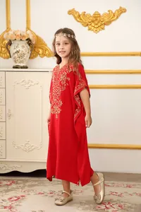 Dettaglio dei ricami dorati su un abito caftano rosso da bambina in ambiente classico