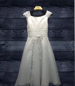 Close-up of white girls' dress with lace straps, floral embroidery and sequin details