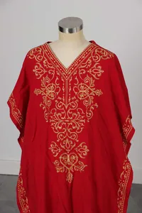Dettaglio di ricami dorati e motivi floreali su abito kaftan rosso in stile etnico