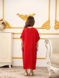 Elegante abito lungo rosso da bambina con ricami dorati in un interno classico