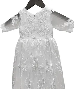 Detalle del encaje bordado floral blanco y mangas transparentes en el vestido de bautizo