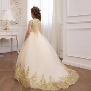 Close-up of luxury champagne flower girl dress with gold sequin embroidery and lace tail