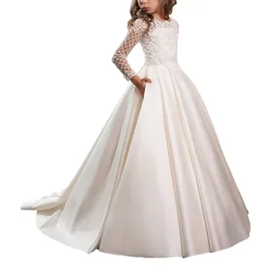 Detail of white flower girl dress featuring lace long sleeves and a satin ball gown skirt