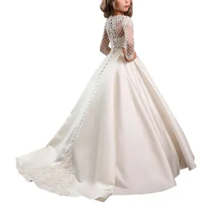Detail of the elegant white lace long sleeves and decorative buttons on a girl's gown