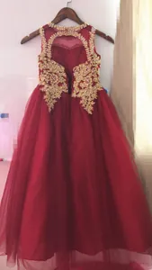 Dettaglio di ricami dorati e perline su tulle rosso di un abito da cerimonia