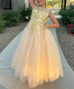 Dettaglio di ricami dorati e scollatura di perle sull'abito da bambina in pizzo champagne
