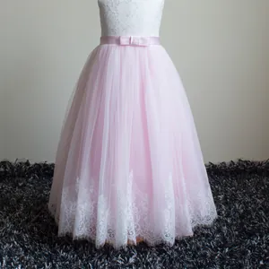 Dettaglio del corpino in pizzo bianco con nastro di raso rosa su vestito da bimba