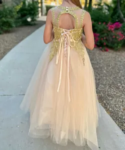 Dettaglio dell'abito da bambina champagne con ricami in pizzo e schiena aperta elegante