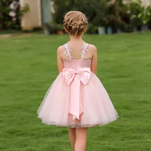 Detailed back view of pink flower girl dress featuring a large bow and lace straps