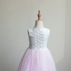 Dettaglio del corpino in pizzo bianco con lacci regolabili sul retro di un abito rosa