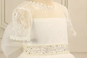 Detail of white lace flower girl dress with sequin and pearl embellishment on the waist