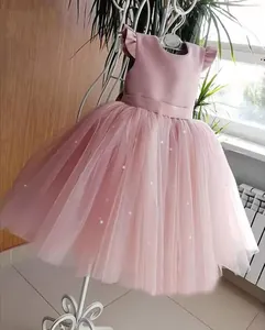 Close-up of pink flower girl dress with delicate pearl accents and soft tulle layers