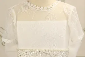 Close-up of lace embroidery, sequins and faux pearls on the white girl's princess dress