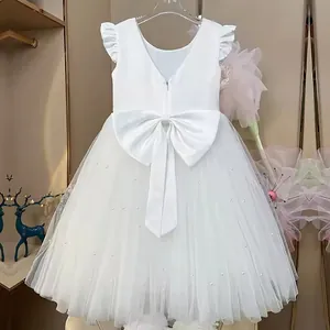 Detailed back view of white flower girl dress with a large satin bow and pearl mesh skirt